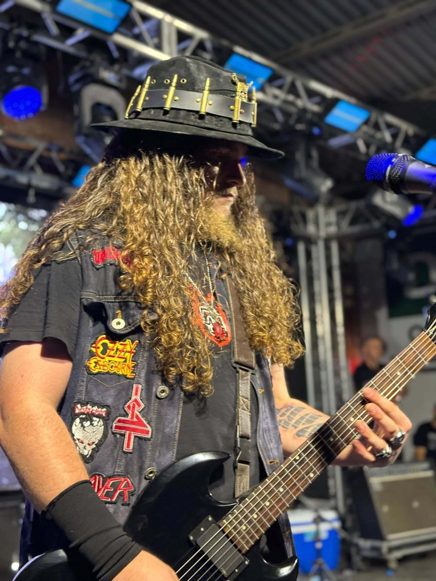 Greg tocando guitarra de chapéu no palco